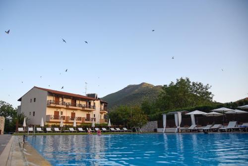 a large swimming pool with a hotel in the background at Mont Helmos Hotel in Klitoria