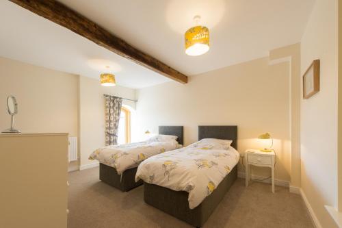 Un dormitorio con 2 camas y una mesa con lámparas. en The Shippen, en Great Chatwell