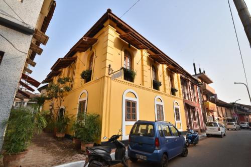 a small blue car parked in front of a yellow building at Mateus Boutique Hotel in Panaji