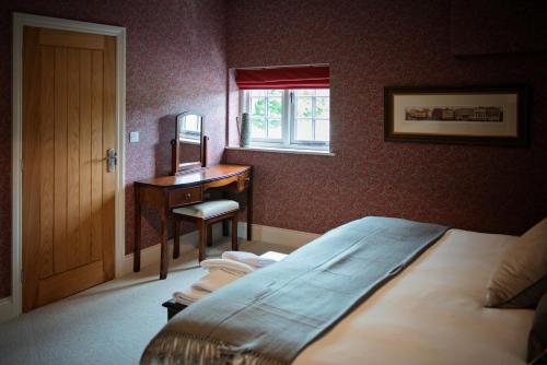 a bedroom with a bed and a desk and a window at The George Great Oxendon in East Farndon