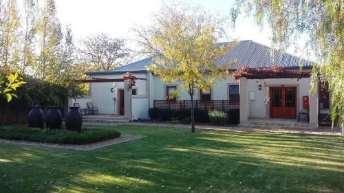 a white house with a lawn in front of it at Honeylocust Guesthouse in Colesberg