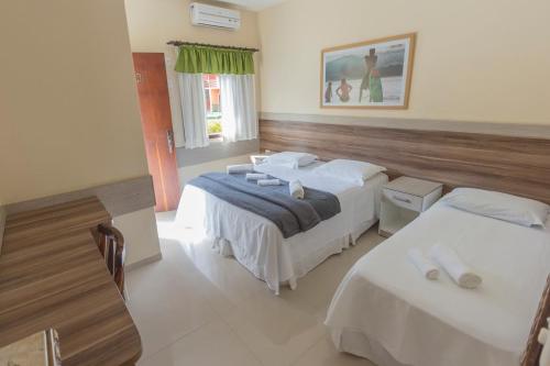 a hotel room with two beds and a window at Hotel Camburi Praia in Camburi