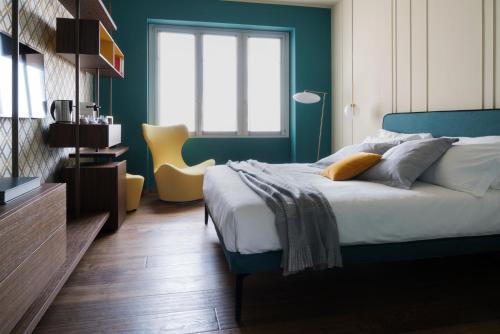 ミラノにあるCastello Sforzesco Suites by Brera Apartmentsの青いベッドルーム(ベッド1台、黄色い椅子付)