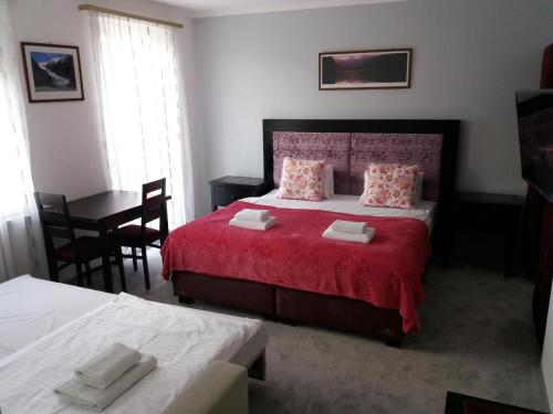 a bedroom with a red bed and a table at Pension Kiwi in Mikulov
