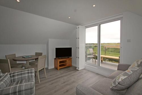 a living room with a television and a table with chairs at Mawgan Porth Apartments in Mawgan Porth