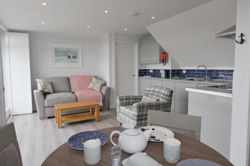 a kitchen and living room with a table and chairs at Mawgan Porth Apartments in Mawgan Porth