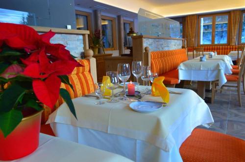 a restaurant with two tables with wine glasses and red flowers at Gästehaus Kristall in Kleinarl