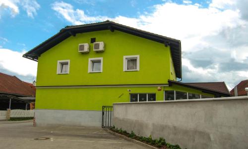 a green building with two windows and a fence at Penzion Pri Slovenc in Dol pri Ljubljani