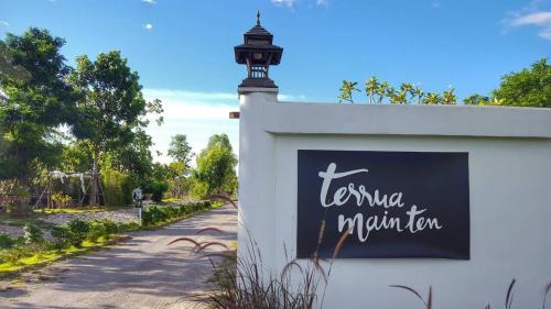 a sign on a wall next to a street with a lighthouse at Terrua Main Ten Villa Garden in Suan Phung