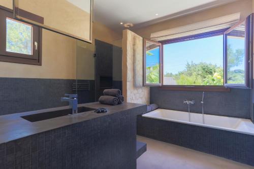 a bathroom with a tub and a sink and a window at Villa Sirio in Cala de Bou