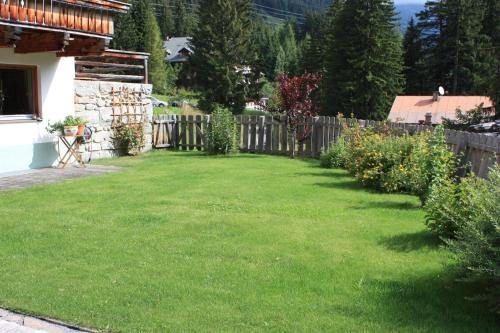 a backyard with a wooden fence and green grass at Pension Sattelkopf in Sankt Anton am Arlberg