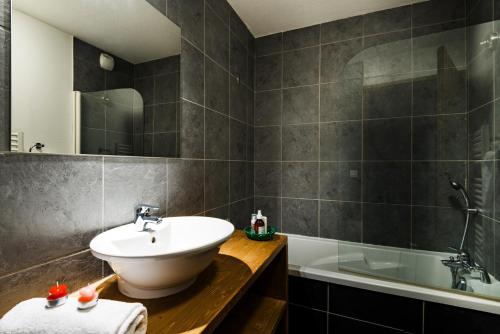 une salle de bain avec un lavabo et une baignoire dans l'établissement travelski home premium - Résidence Les Chalets d'Edelweiss, à Plagne 1800