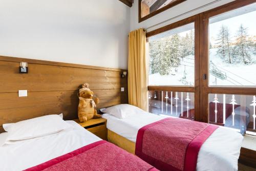- une chambre avec deux lits et un ours en peluche assis à côté d'une fenêtre dans l'établissement travelski home premium - Résidence Les Chalets d'Edelweiss, à Plagne 1800
