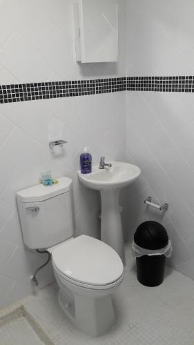 a white bathroom with a toilet and a sink at Hotel Casa Conley Del Mar in Puerto Viejo