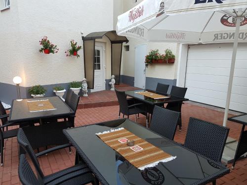 eine Terrasse mit Tischen, Stühlen und einem Sonnenschirm in der Unterkunft Hotel Restaurant Rhodos in Elsterwerda