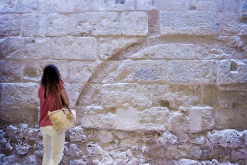 a woman standing in front of a stone wall at Sindic Hotel - Adults Only in Mahón