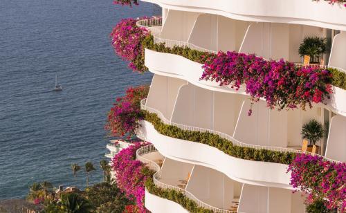 a building with pink flowers on it next to the ocean at Grand Miramar All Luxury Suites & Residences in Puerto Vallarta