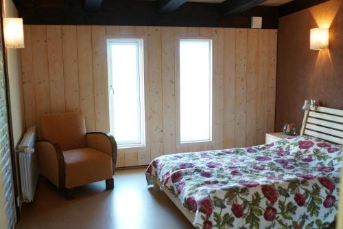 ein Schlafzimmer mit einem Bett und einem Stuhl sowie zwei Fenstern in der Unterkunft Aasavälja Rannamaja in Kabli