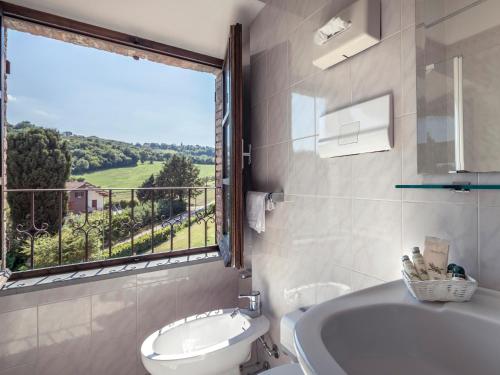 グッビオにあるHotel Villa Montegranelliのバスルーム(洗面台、トイレ付)、窓が備わります。