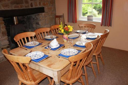 a wooden table with chairs and plates and glasses at Church Hill Farm in Monmouth