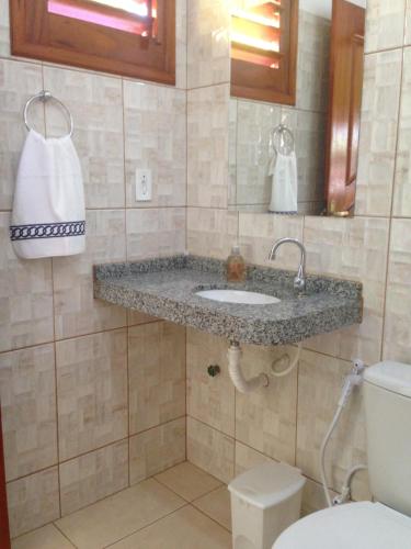La salle de bains est pourvue d'un lavabo et de toilettes. dans l'établissement Pousada Muiraquitã, à Beberibe