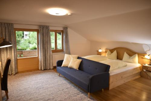 a bedroom with a bed and a couch and a window at Gästehaus Alte Bergmühle in Fischbachau