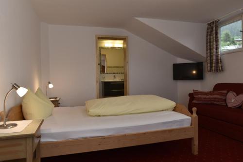 een kleine slaapkamer met een bed en een bank bij Gästehaus Alte Bergmühle in Fischbachau