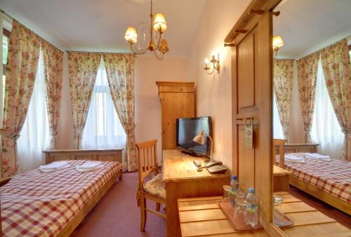sypialnia z 2 łóżkami i biurkiem z telewizorem w obiekcie Hotel Magnes w Szklarskiej Porębie