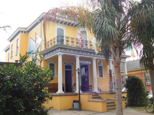 a yellow house with a balcony and a palm tree at India House Hostel in New Orleans
