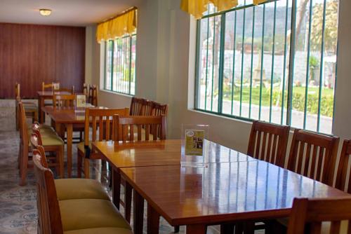 a restaurant with wooden tables and chairs and windows at El Cano in Guaillabamba