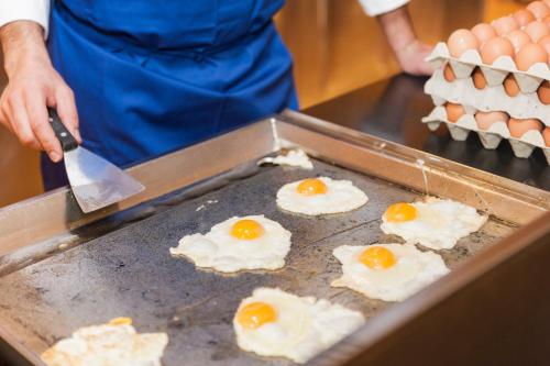 a person cooking eggs on a grill with a knife at Hotel Mediterraneo in Benidorm