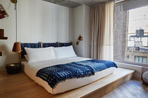 a bedroom with a large bed with a window at MADE Hotel in New York