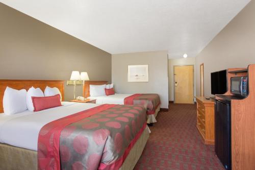 a hotel room with two beds and a flat screen tv at Ramada by Wyndham St George in St. George