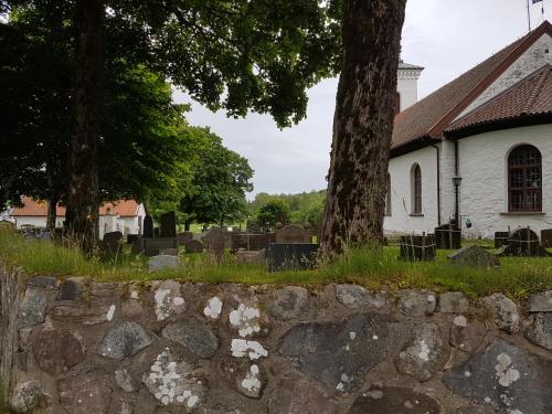 a church with a stone wall in front of a cemetery at Alkoven Logi in Ullared