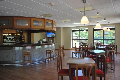 ein Restaurant mit einer Bar sowie Tischen und Stühlen in der Unterkunft Hotel Principado De Europa in Las Arenas