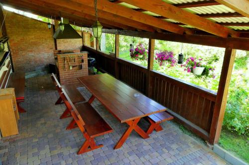 una mesa de madera y sillas en un porche cubierto en Hotel Pod Kamykiem, en Rząska