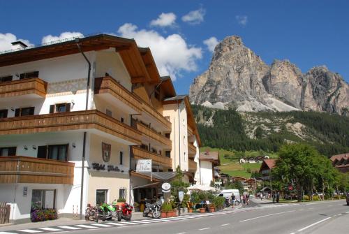 un bâtiment situé sur le côté d'une rue avec une montagne dans l'établissement Hotel Italia, à Corvara in Badia