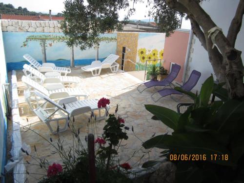 a patio with white chairs and a mural at Apartments Villa Bella Vista Hvar in Hvar