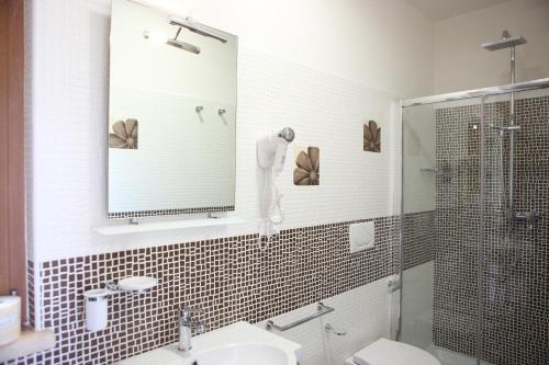 ein Bad mit einer Dusche, einem Waschbecken und einem Spiegel in der Unterkunft Agriturismo Poggio al Sasso in Blera
