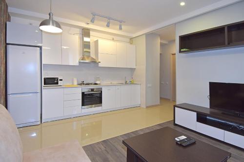 a large kitchen with white cabinets and a tv at Pushkin 49 in Yerevan