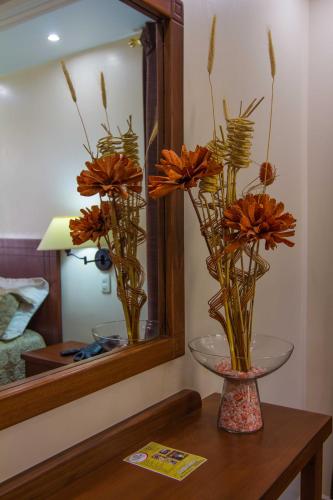 a vase with orange flowers on a table in front of a mirror at El Cano in Guaillabamba