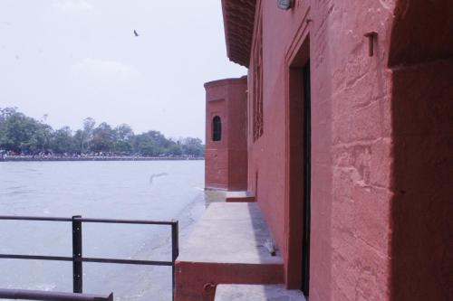 a red building next to a body of water at Patnimal Guesthouse in Haridwār