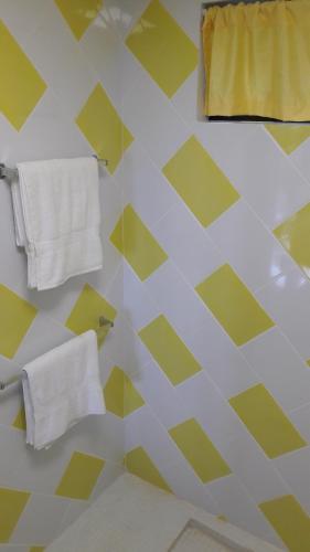 a bathroom with yellow and white walls and towels at Hotel Casa Conley Del Mar in Puerto Viejo