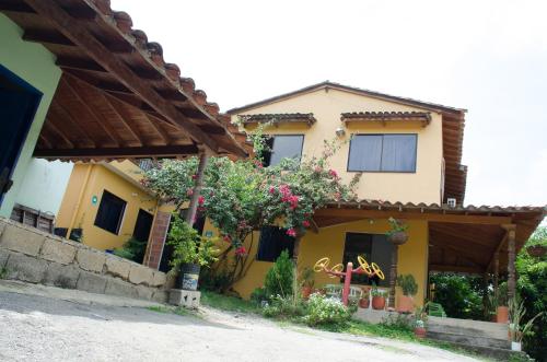 una casa amarilla con flores a un lado. en Hospedaje la Glorieta, en Santa Fe de Antioquia