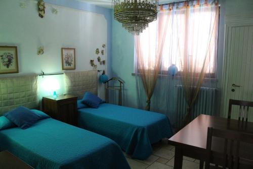 a bedroom with two beds and a table and a chandelier at Morgana in Castrezatto