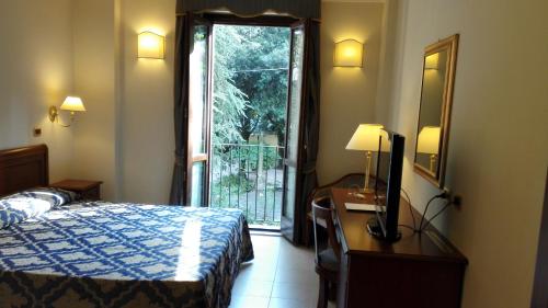 a hotel room with a bed and a desk and a window at Villa Cattani Stuart XVII secolo in Pesaro