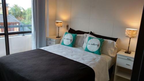 a bedroom with a bed with blue pillows and a window at Apartamento Plaza San Martin in Concepción del Uruguay