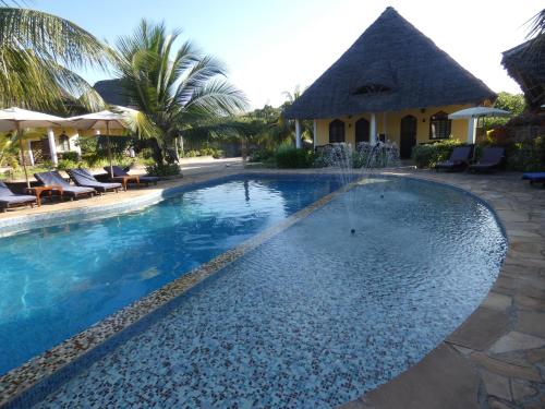 a pool at a resort with chairs and umbrellas at Kiwengwa Bungalow Boutique Resort in Kiwengwa