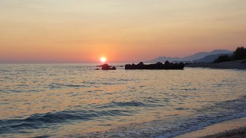 a sunset on the beach with a boat in the water at Triantis Apartments in Ligia