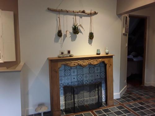 a fireplace in a living room with a wooden mantle at Au Moulin de Valérie in Frencq